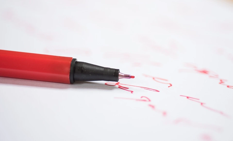 Stylo rouge sur une feuille papier avec des écritures rouge